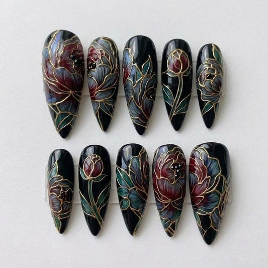 Macro view of intricate hand-painted floral nail art with gold line-work on a deep black background, showcasing high-end craftsmanship in gothic-style press-ons.