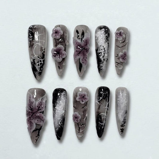 Elegant dark-themed stiletto press-on nails featuring hand-painted floral embellishments.
