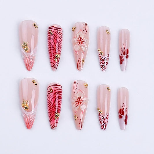 Ten pieces of JRNAIL long stiletto press-on nails featuring hand-painted cherry blossoms, leopard tips, pink tiger stripes, and 3D gold bead embellishments on a clean white background.