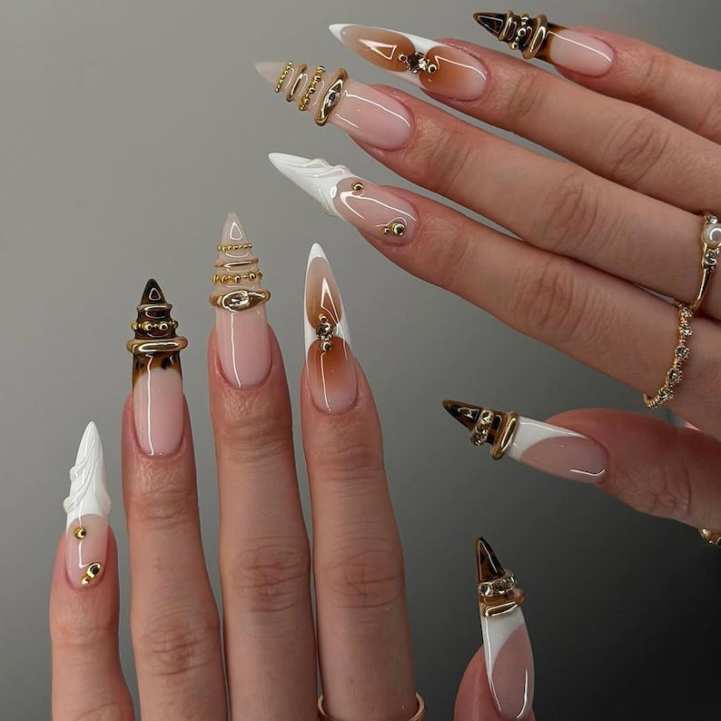 Close-up of hands with long, decorative nails and gold rings on a neutral background