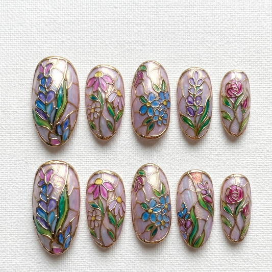 Luxury almond-shaped press-on nails with artisanal floral patterns and cathedral-inspired gold detailing for a sophisticated, unique manicure.