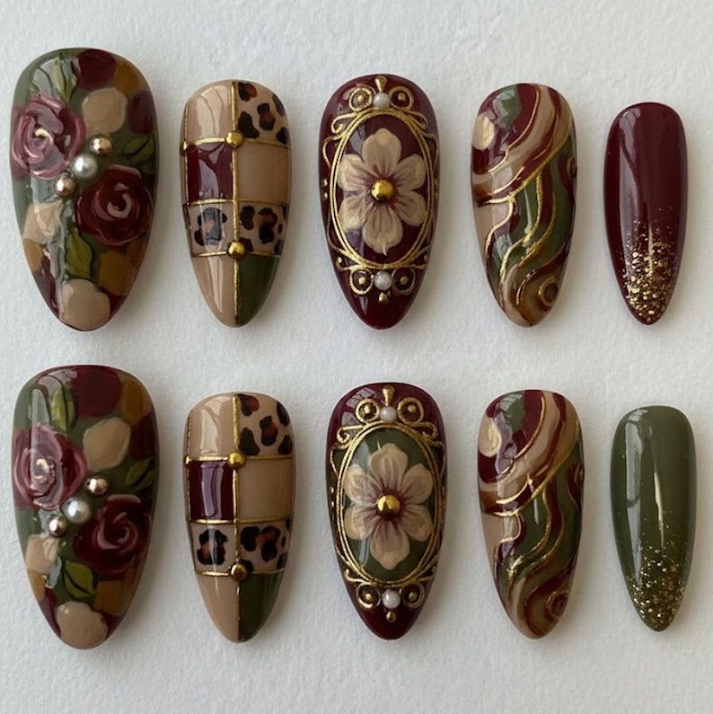 Sophisticated almond-shaped press-on nails with a burgundy and sage green color palette, adorned with gold frames and pearl details.
