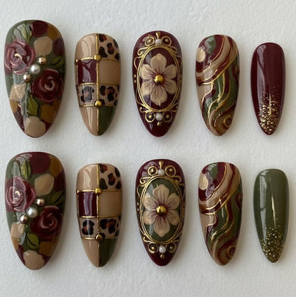 Sophisticated almond-shaped press-on nails with a burgundy and sage green color palette, adorned with gold frames and pearl details.