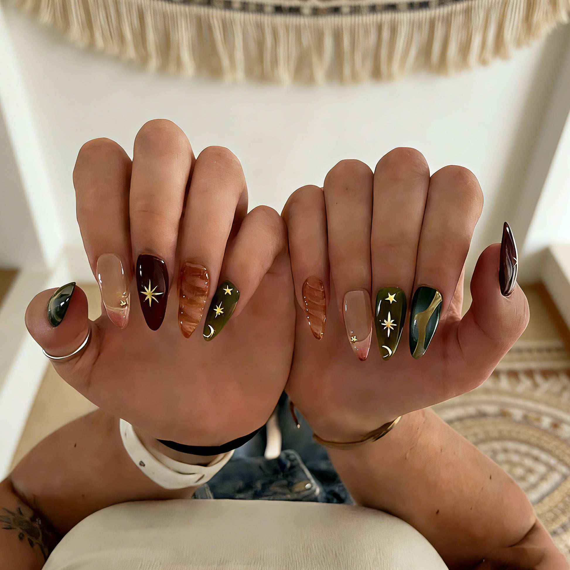 Luxury bohemian fake nails with gold foil, 3D amber swirls, and celestial motifs on glossy almond-shaped press ons