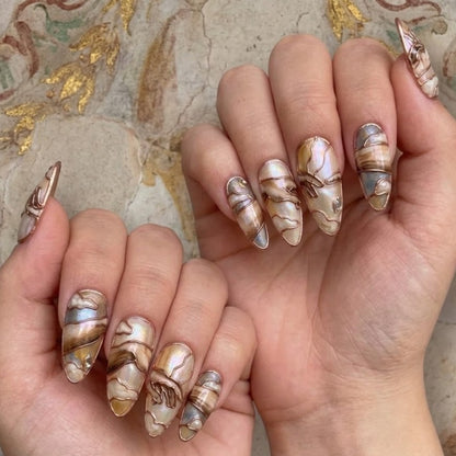 These stiletto-shaped press-on nails feature an exquisite, intricate classical design with marble swirls in brown, cream, and iridescent blue. Copper wire and pearl details add a luxurious touch.