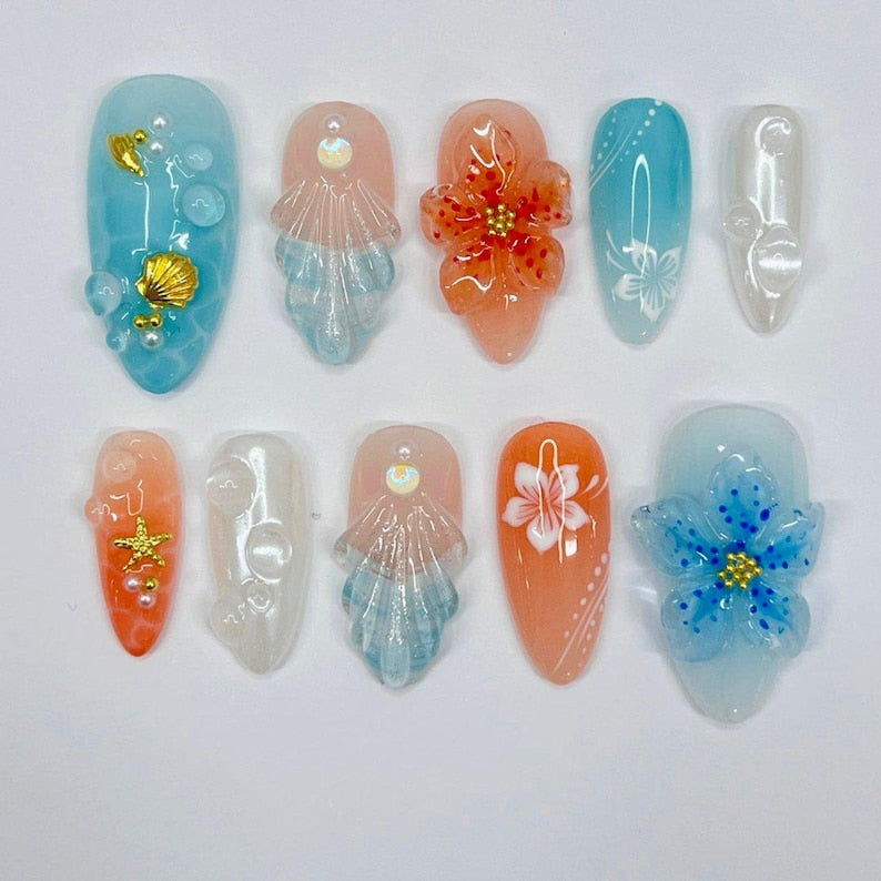 Pastel ocean press on nails with 3D gold shell accents, water-like gradients, and floral motifs