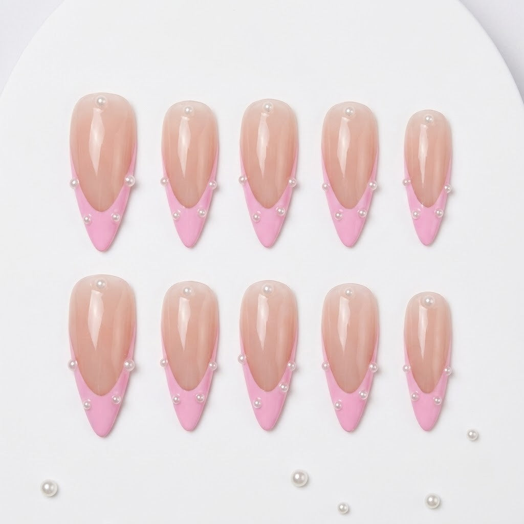 Close-up of handmade coquette false nails showcasing a high-gloss sheer pink base, crisp bubblegum pink French tip smile lines, and precisely placed mini pearls along the border.