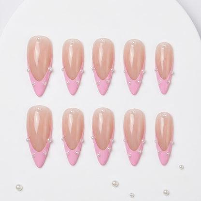 Close-up of handmade coquette false nails showcasing a high-gloss sheer pink base, crisp bubblegum pink French tip smile lines, and precisely placed mini pearls along the border.