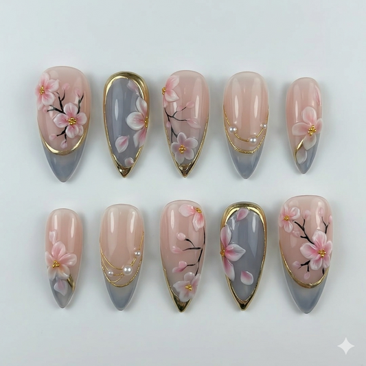 Macro view of hand-painted sakura flowers on luxury gel nails, highlighted by shimmering gold foil and minimalist pearl details
