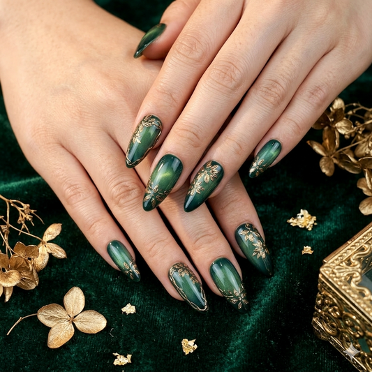 Close-up of hands with green nail polish and gold accents on a green fabric background.
