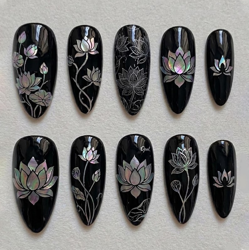 Luxury almond-shaped press-on nails with mother-of-pearl lotus art on a glossy black base, perfect for a sophisticated, artistic look.