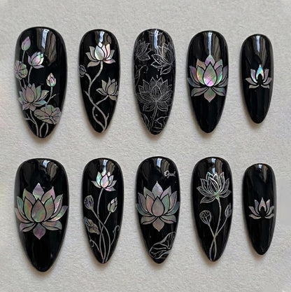 Luxury almond-shaped press-on nails with mother-of-pearl lotus art on a glossy black base, perfect for a sophisticated, artistic look.