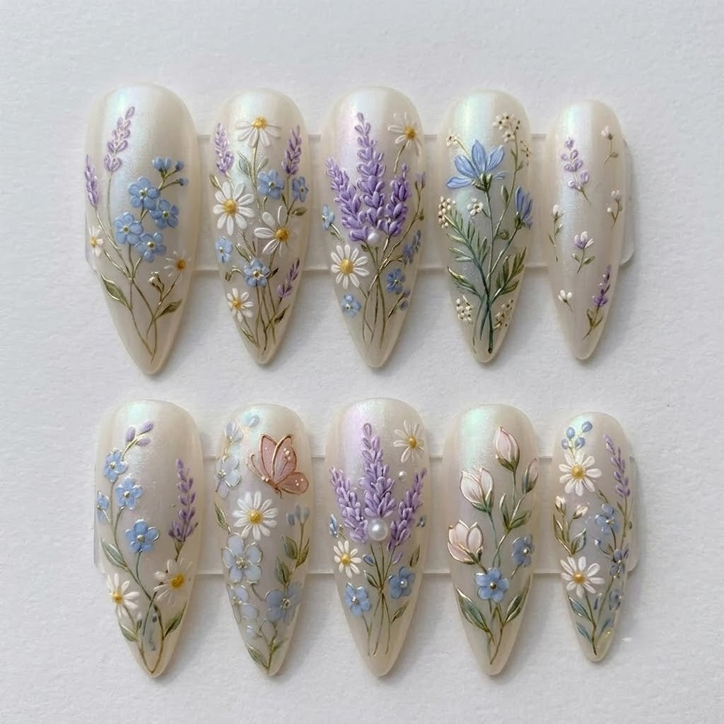 Close-up shot of JRNAIL handmade 3D floral press-on nails with lavender and daisy designs laid out flat on a clean white background.