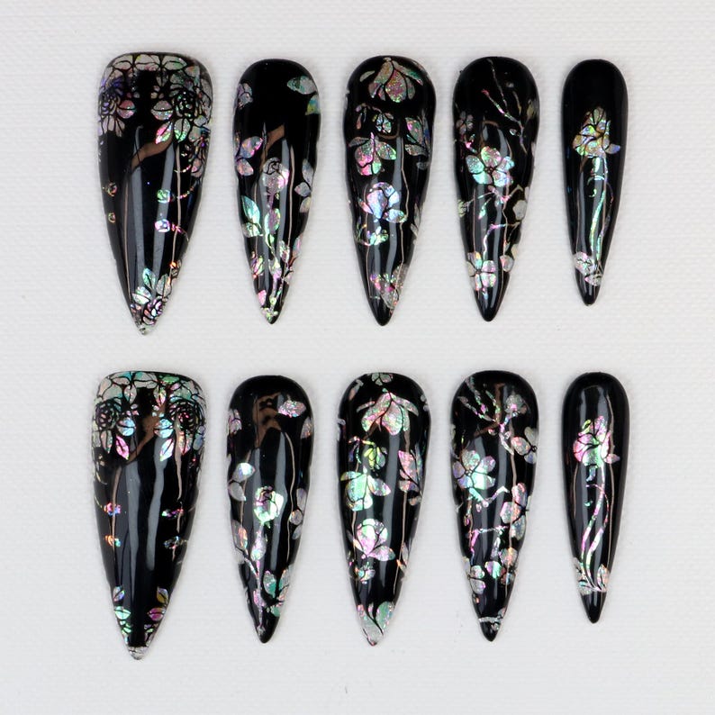 Gothic stiletto press-on nails featuring aurora shell flower nail art on black base