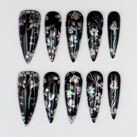 Gothic stiletto press-on nails featuring aurora shell flower nail art on black base