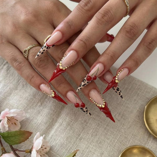 Long stiletto press-on nails with red cherry 3D art and leopard print on nude base