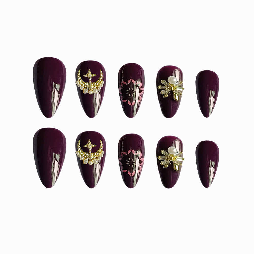 Glossy plum stiletto press ons with gold star moon embellishments and pink flower art