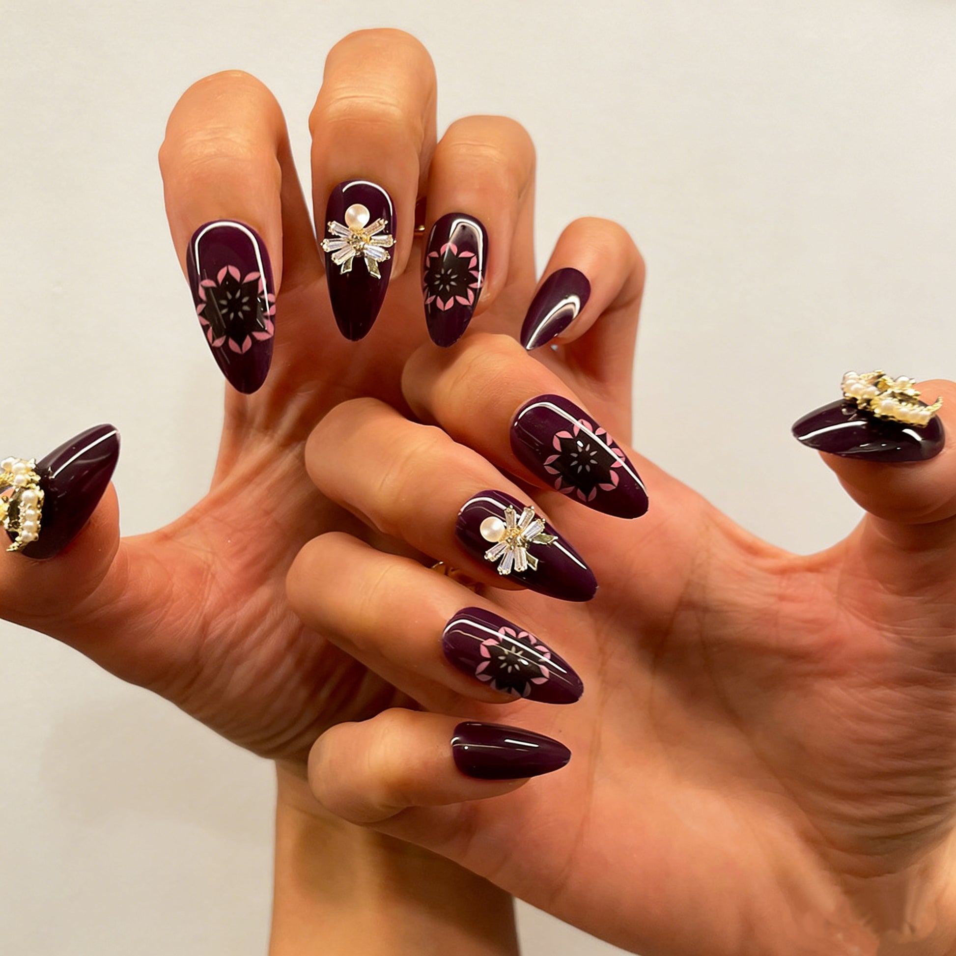 Luxury dark purple fake nails featuring celestial pearl charms and delicate floral patterns