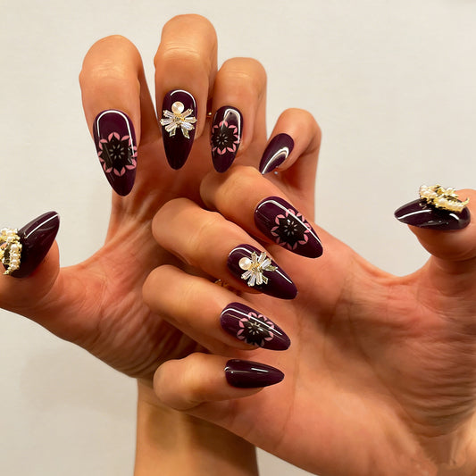Luxury dark purple fake nails featuring celestial pearl charms and delicate floral patterns
