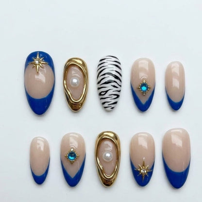 Close-up of a premium salon-quality manicure set displaying 24 pieces of almond-shaped false nails adorned with striking blue gel color, abstract animal prints, and intricate rhinestone star details.
