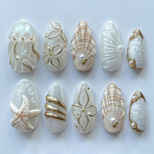 3D coastal fake nails with seashell motifs, gold foil details, and pearl embellishments for summer