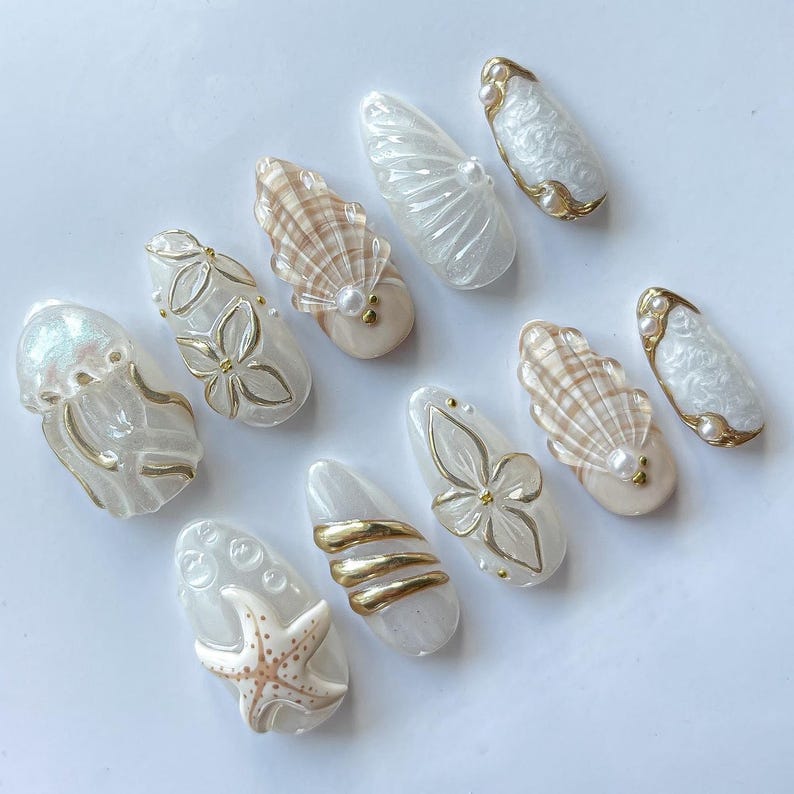 Mermaid-inspired press on nails with 3D jellyfish, starfish, and gold foil on iridescent white base