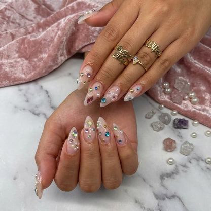 JRNAIL trendy Y2K stiletto fake nails displaying a glossy crystal-clear texture encrusted with colorful geometric gemstones and pearls, perfect for a high-glam DIY festival manicure or statement birthday look.