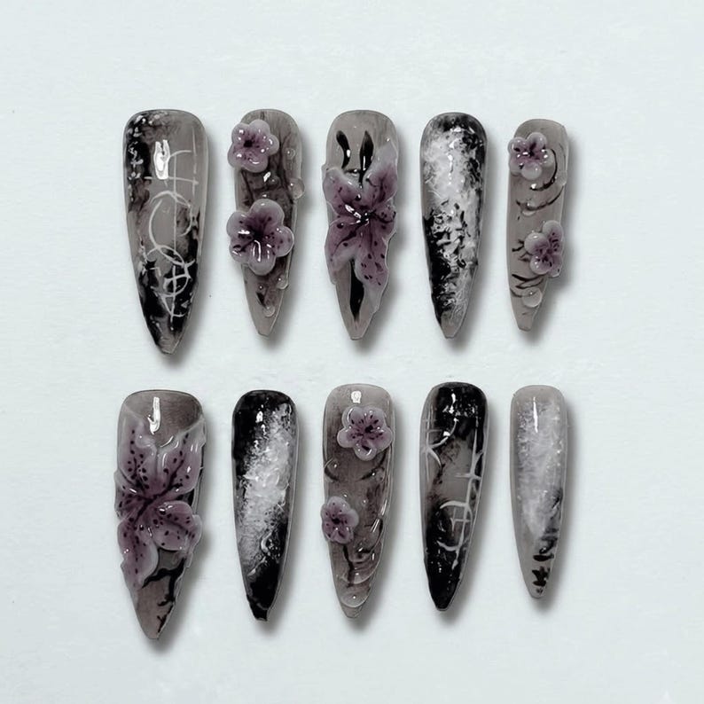 Elegant dark-themed stiletto press-on nails featuring hand-painted floral embellishments.