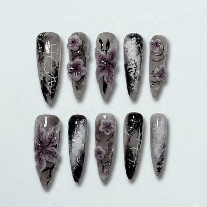 Elegant dark-themed stiletto press-on nails featuring hand-painted floral embellishments.