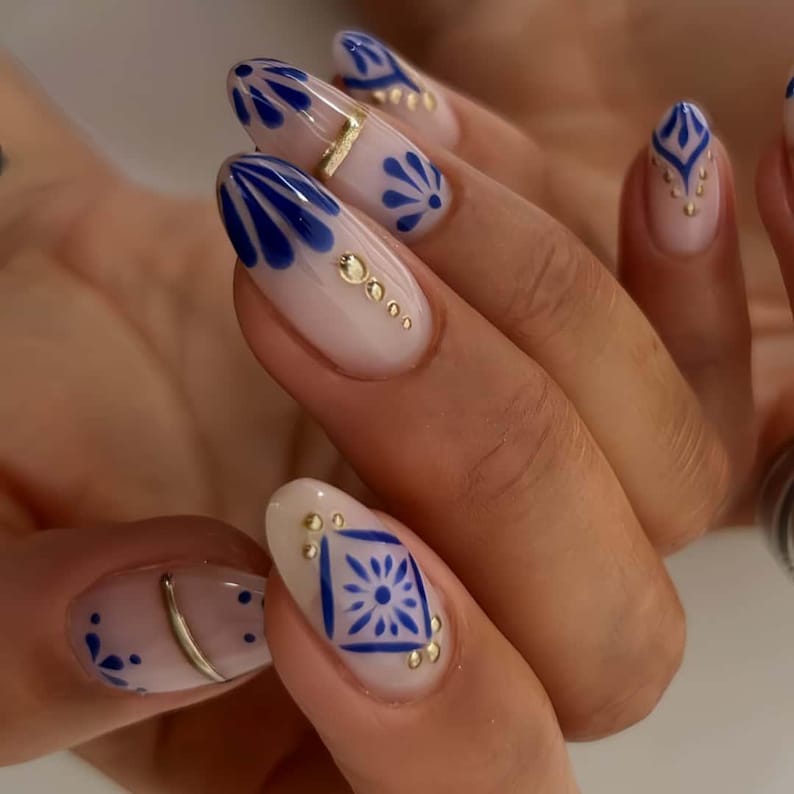Nude almond nails with blue floral design and gold foil accents