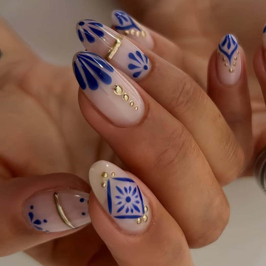 Nude almond nails with blue floral design and gold foil accents