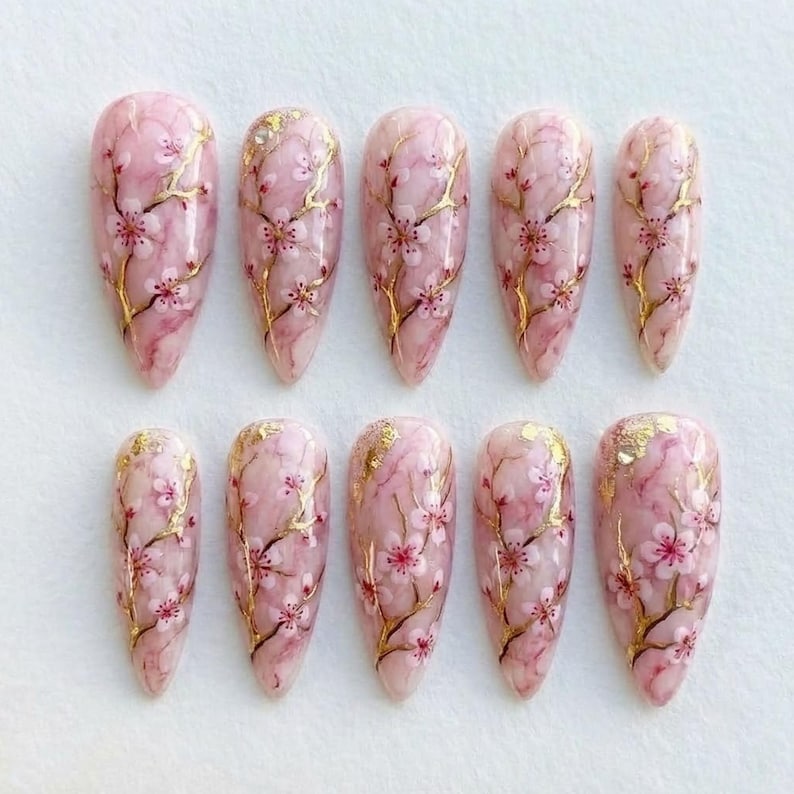 Elegant pink marble nail art set featuring delicate sakura flower patterns for a romantic look.