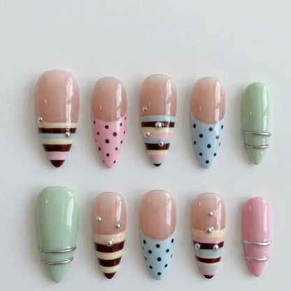 Close-up of elegant stiletto-shaped reusable false nails decorated with a mix of multi-colored circus stripes, mint green, blush pink, and delicate silver crystal clusters.