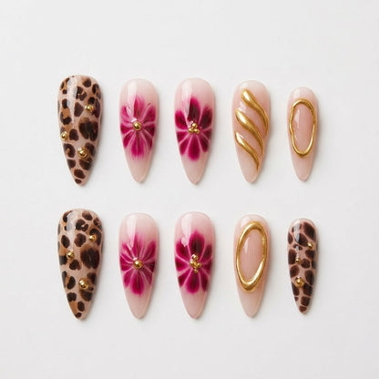 Close-up of premium handmade false nails displaying a mix of translucent nude bases, bold animal print detailing, and heavy textured gold chrome accents with miniature gems