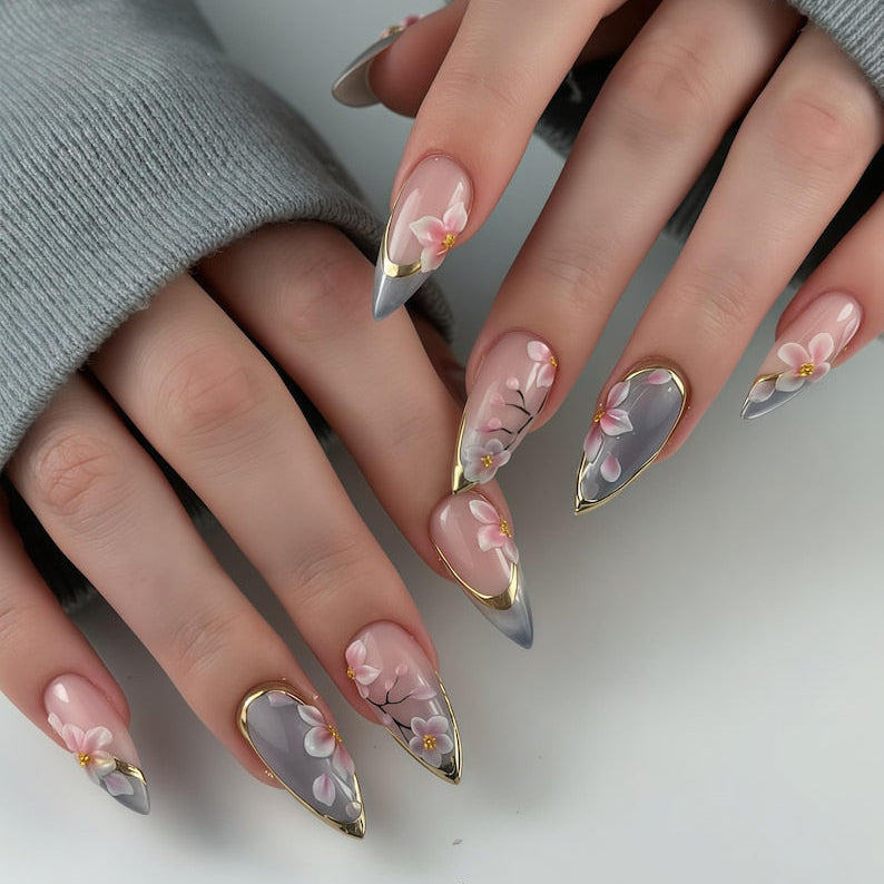 A luxury set of handmade press-on nails featuring delicate cherry blossom art, elegant gold leaf accents, and a soft grey-nude gradient base by JRNAIL.