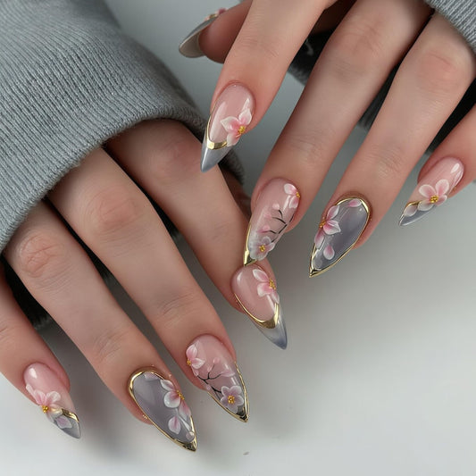 A luxury set of handmade press-on nails featuring delicate cherry blossom art, elegant gold leaf accents, and a soft grey-nude gradient base by JRNAIL.