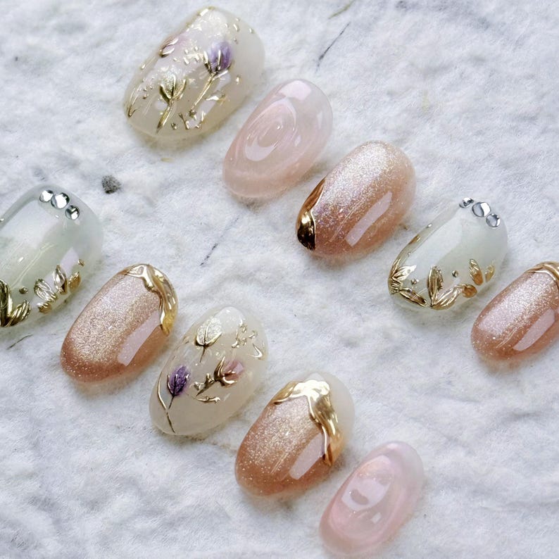 Close-up of the velvet cat eye effect on almond-shaped gel press-on nails reflecting a soft champagne shimmer with gold French V-cut tips.
