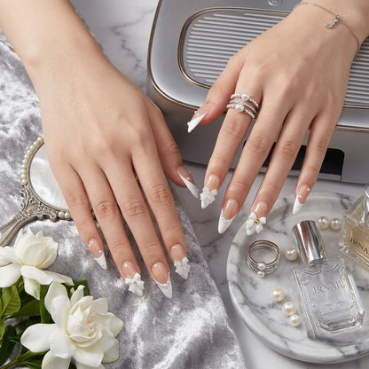 JRNAIL elegant minimalist stiletto fake nails displaying a glossy gel finish, dimensional white bows, and pearlescent details, ideal for a chic DIY home manicure or bridal look.