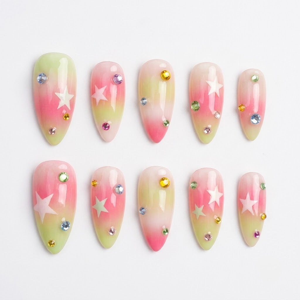 Close-up of premium reusable false nails featuring a soft pastel green and hot pink airbrushed blush gradient, decorated with crisp white stars and scattered colorful rhinestone crystals.