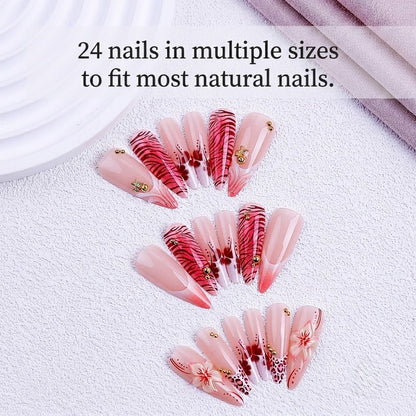 A close-up of 24pcs JRNAIL long pointy press-on nails decorated with cherry blossoms, tiger stripes, and leopard patterns with crystals and makeup brushes nearby.