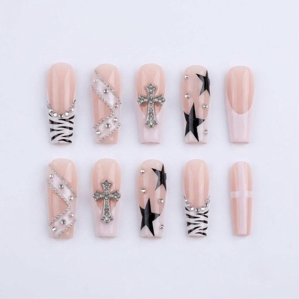 A complete layout of JRNAIL gothic punk press-on nails featuring black stars, zebra print tips, and 3D metallic cross charms with rhinestones on a white textured background.