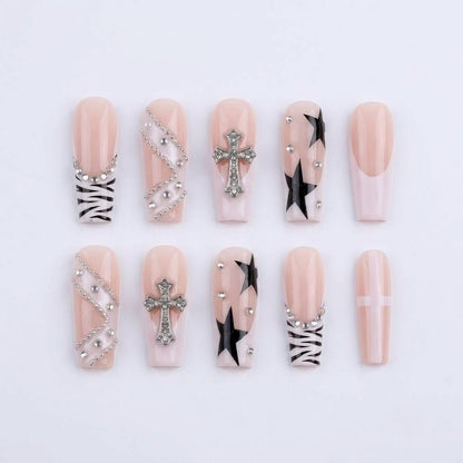 A complete layout of JRNAIL gothic punk press-on nails featuring black stars, zebra print tips, and 3D metallic cross charms with rhinestones on a white textured background.