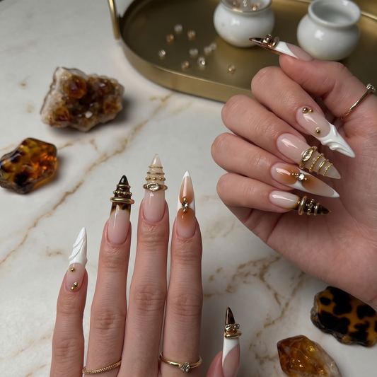 Hand model showcasing JRNAIL's tortoiseshell and amber ombré press-on nails with 3D gold ring hardware over a luxury marble background.