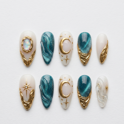 A close-up of a luxury witchy manicure featuring magnetic teal gel fake nails and gold foil accents, accessorized with chunky gold rings.