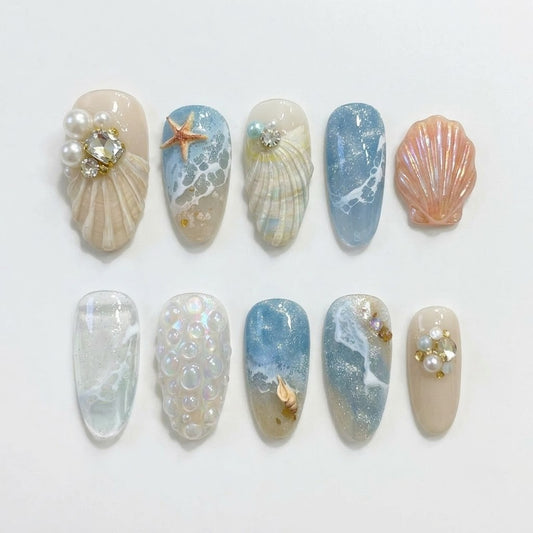 Beach-inspired false nails with 3D ocean waves, pearlescent shells, and starfish accents, showcasing a full 30-piece multi-size set for natural nails.